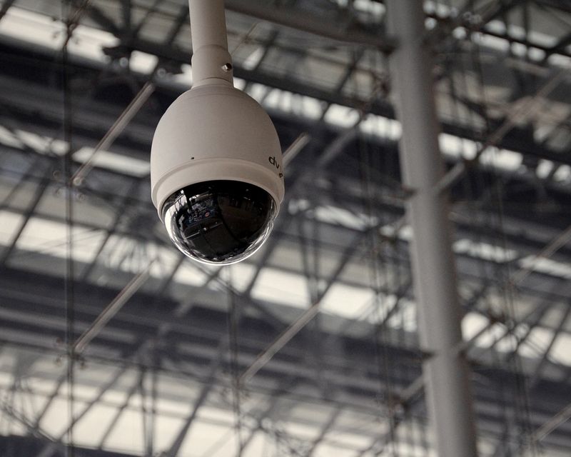 Dome security camera suspended beneath a steel roof structure