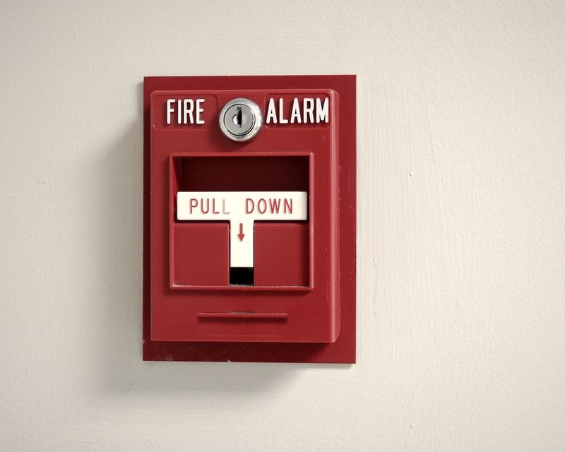 Red fire alarm pull station on a clean white wall